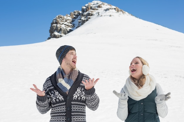 Pareja con las manos abiertas de pie frente a la colina nevada