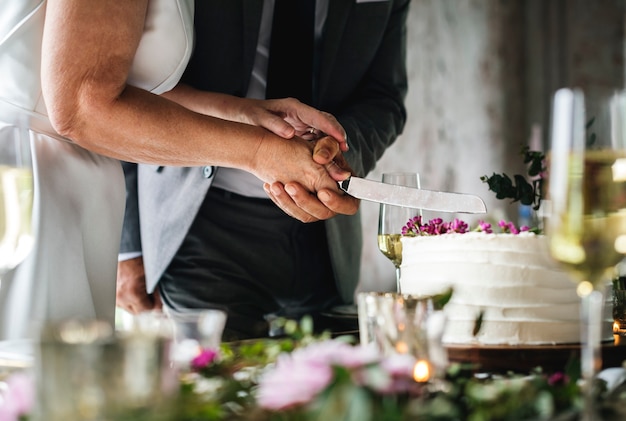 Pareja manos cortar pastel de boda