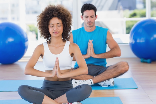 Pareja con las manos juntas y los ojos cerrados en el gimnasio