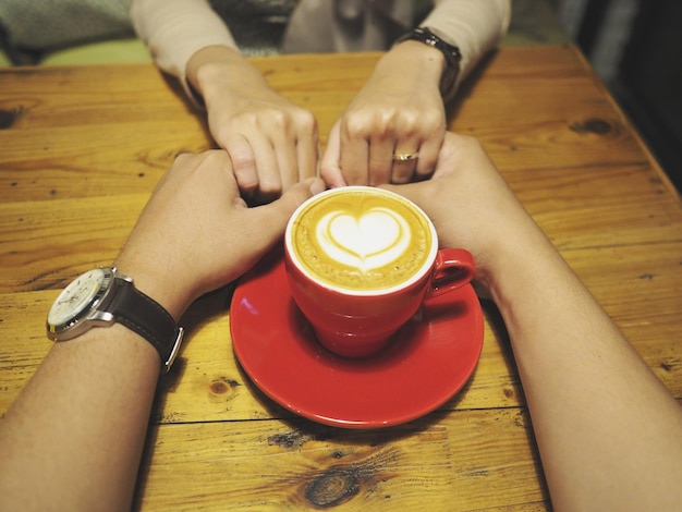 Foto una pareja de manos en la taza de café en la mesa