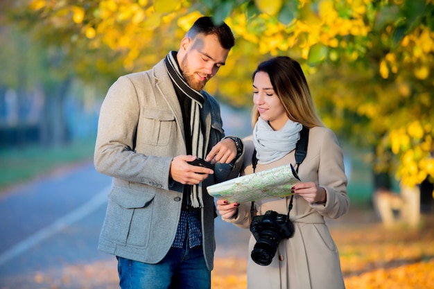 Pareja con mapa y cámara en callejón otoño de la ciudad.