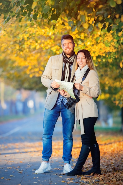 Pareja con mapa y cámara en callejón otoño de la ciudad.