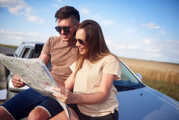 Pareja con mapa eligiendo la mejor carretera para viaje por carretera