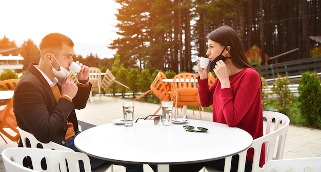 Foto pareja con máscara médica protectora tomando café en un restaurante, nuevo concepto normal de coronavirus