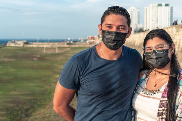 Foto pareja con máscara protectora compartiendo al aire libre