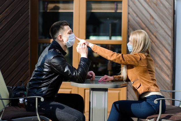 Pareja con máscaras protectoras da un paseo al aire libre en la ciudad cerca del edificio comercial en el momento de la cuarentena. Concepción de coronavirus.