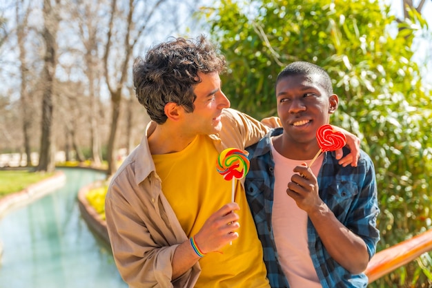 Pareja masculina gay multiétnica comiendo una piruleta concepto lgbt diversión romántica