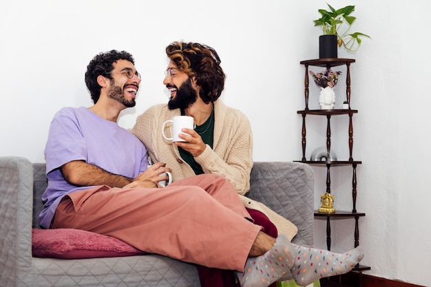 Una pareja masculina riéndose relajada en el sofá de casa