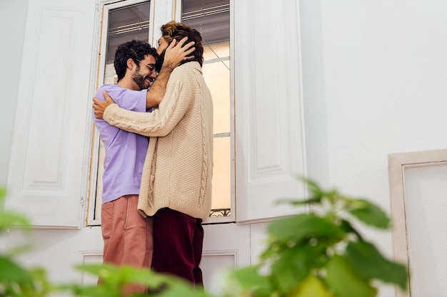 Pareja masculina sonriendo feliz y besándose en casa