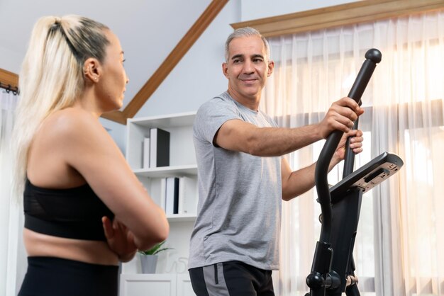 Foto pareja mayor activa corriendo en una máquina elíptica en casa juntos como estilo de vida saludable y cuidado del cuerpo después de la jubilación para el pensionista clout