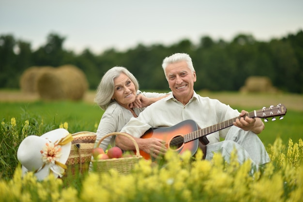 Pareja mayor, con, guitarra, en, verano, campo, con, flores