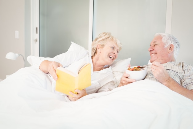 Pareja mayor, libro de lectura, en cama