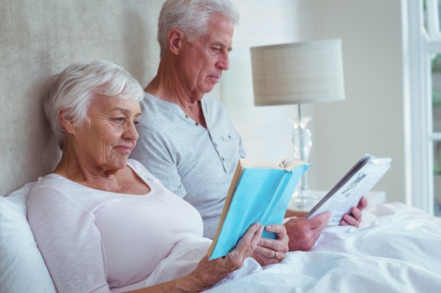 Pareja mayor, libro de lectura, en cama