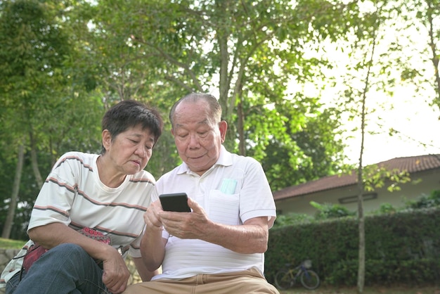 Pareja mayor navegando y leyendo el teléfono juntos en el parque