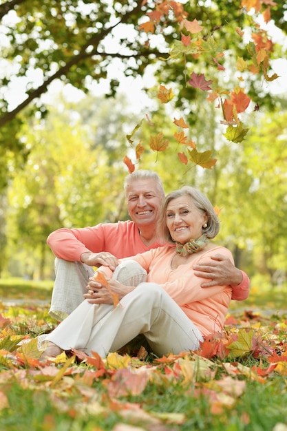 Pareja mayor sentada en hojas de otoño en el parque