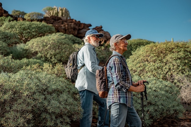 Una pareja mayor sonriente disfrutando de una excursión al aire libre en un entorno montañoso con un estilo de vida saludable