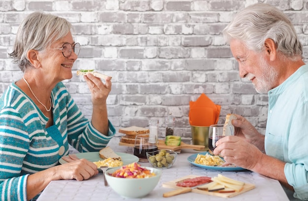 Una pareja mayor sonriente sentada cara a cara en la mesa de casa disfrutando del brunch o el desayuno juntos en casa serena jubilación