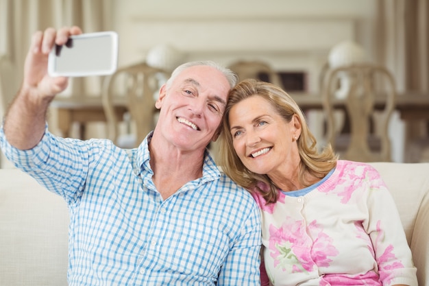 Pareja mayor, toma, un, selfie, en, teléfono móvil, en, sala