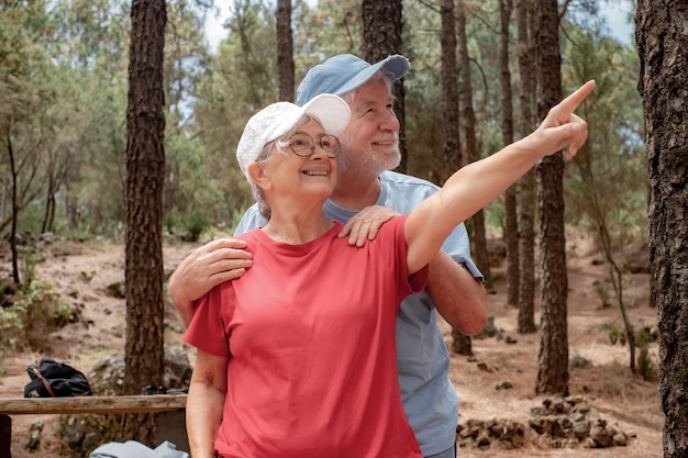 Una pareja de mayores feliz abrazándose disfrutando de una caminata por la montaña en el bosque apreciando la naturaleza y la libertad