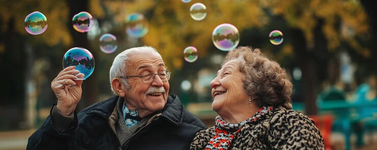Una pareja de mayores feliz jugando con burbujas de jabón en el parque