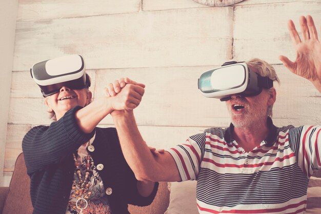 Foto una pareja de mayores mirando a través de un simulador de realidad virtual mientras están sentados en el sofá en casa