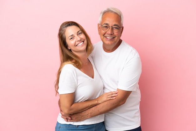 Pareja de mediana edad aislada sobre fondo rosa abrazos