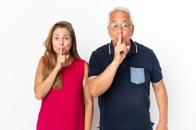 Pareja de mediana edad aislado sobre fondo blanco que muestra un signo de cerrar la boca y el gesto de silencio