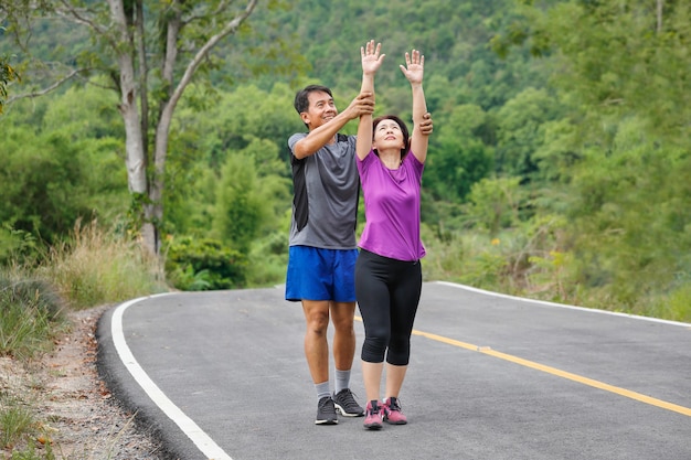 Pareja de mediana edad asiática estirando los músculos antes de trotar en el parque