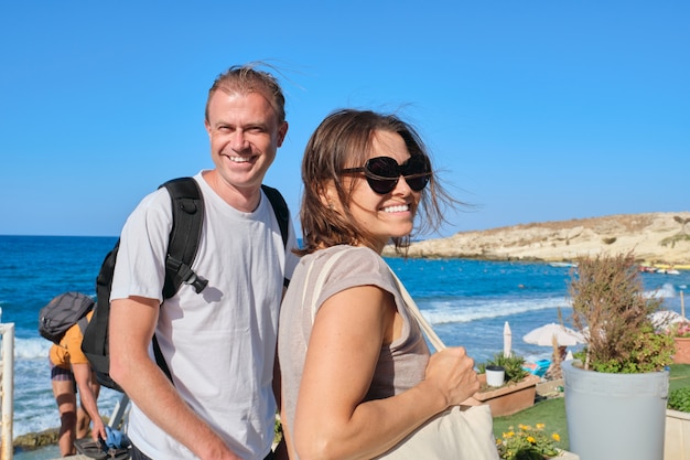 Pareja de mediana edad caminando cogidos de la mano, hombre y mujer viajando juntos