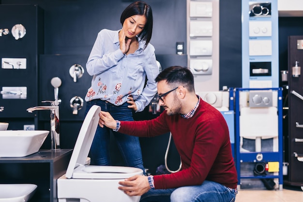 Pareja de mediana edad eligiendo nuevos azulejos y utensilios de cerámica para su baño.