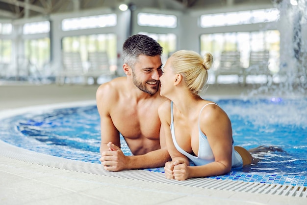 Una pareja de mediana edad enamorada en traje de baño se relaja y coquetea en la piscina con agua termal