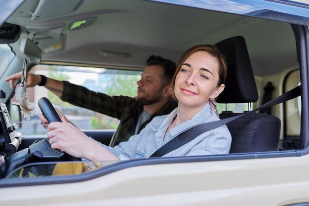 Pareja de mediana edad montando en coche mujer conductor hombre en asiento de pasajero