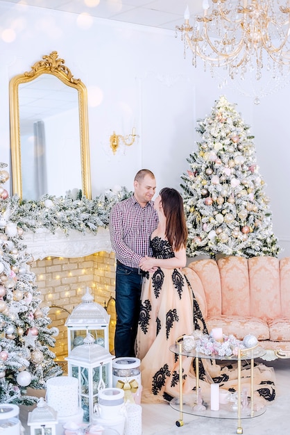 Una pareja de mediana edad en ropa elegante contra un interior de árboles de nieve de Navidad