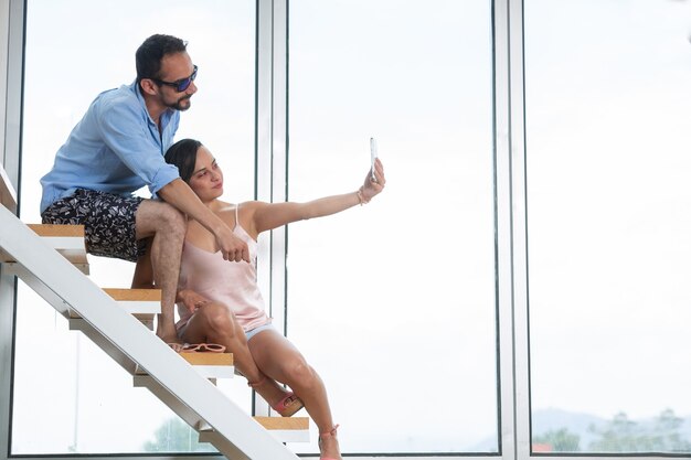 Pareja mexicana tomando selfie de verano en escaleras y ventana grande