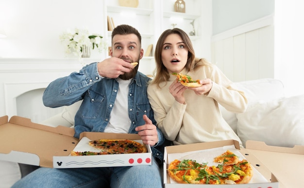 Foto pareja milenaria viendo películas de terror y comiendo pizza