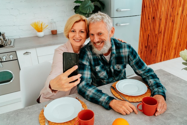 Pareja miling toma un selfie con un teléfono inteligente durante el desayuno