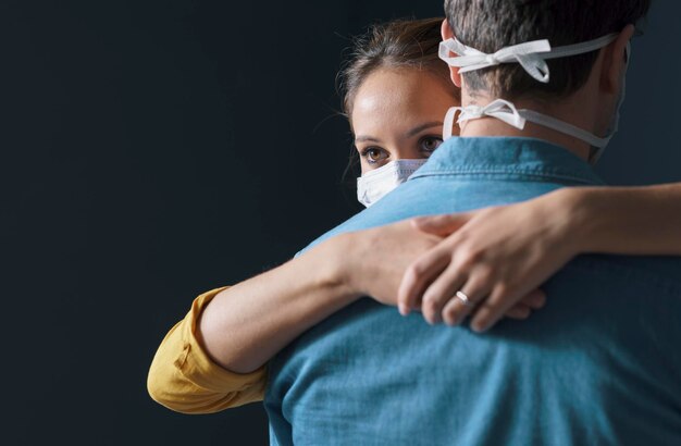 Pareja de millennials con mascarilla protectora y abrazos