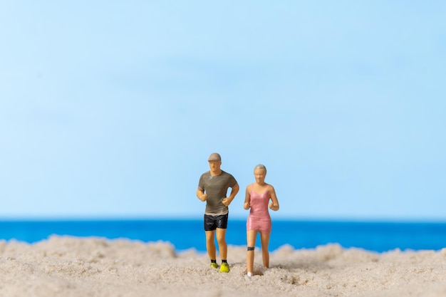 Pareja en miniatura corriendo juntos en la playa