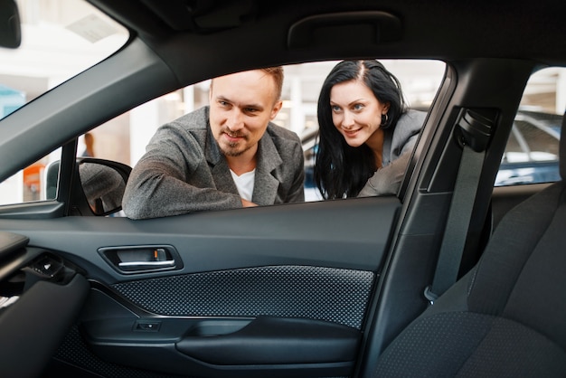 La pareja mira el interior del coche nuevo en la sala de exposiciones.