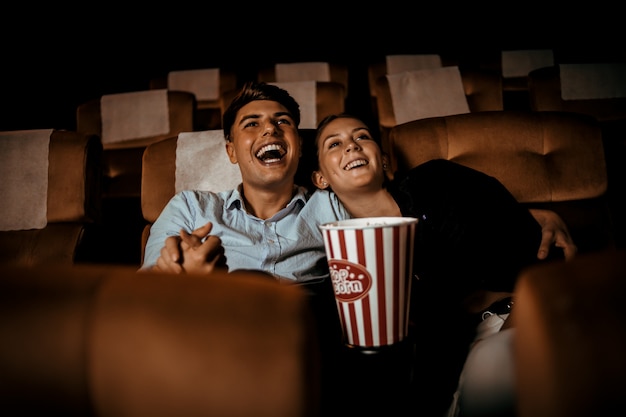 Pareja mira películas en el teatro con palomitas de maíz sonrisa y cara feliz