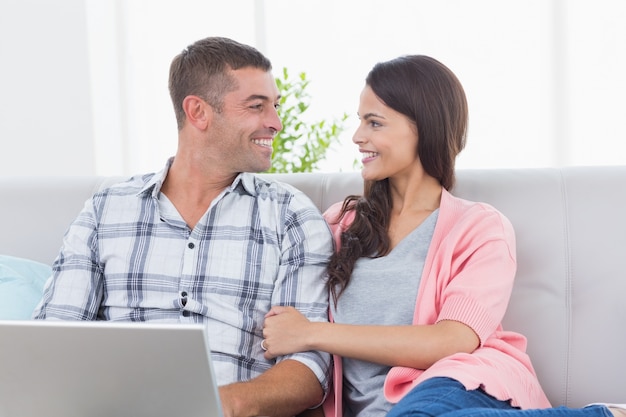 Pareja mirando el uno al otro mientras usa la computadora portátil