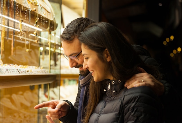 Pareja mirando el escaparate de una joyería al aire libre.