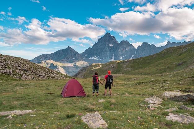 Pareja mirando la majestuosa vista de los picos de las montañas al atardecer en lo alto de los Alpes