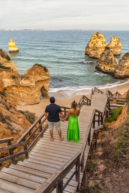 Pareja mirando el mar bajando los escalones de la playa Camilo en Lagos, Algarve, Portugal.