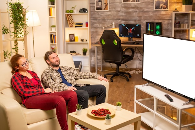 Pareja mirando la pantalla de TV blanco aislado a altas horas de la noche en la sala de estar.