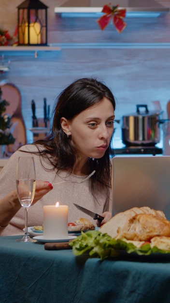 Pareja mirando portátil y comiendo comida festiva