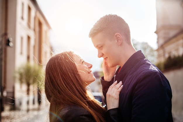 Pareja mirándose entre sí mientras están de pie en medio de edificios contra el cielo