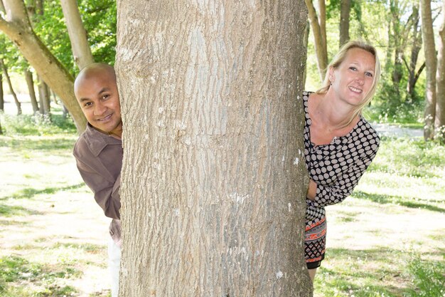 Pareja mixta enamorada jugando al escondite en un parque