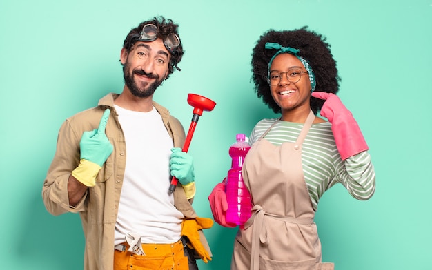 Pareja mixta sonriendo con confianza apuntando a su propia sonrisa amplia, actitud positiva, relajada y satisfecha. concepto de limpieza ... concepto de reparaciones del hogar