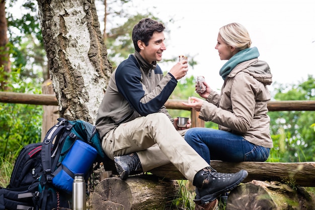 Pareja de mochileros tomando descanso a un lado sendero